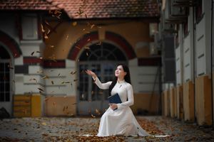 Elegant Vietnamese student in white Ao Dai reading, timeless beauty amidst classic architecture.-4