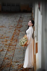 Elegant Vietnamese student in white Ao Dai reading, timeless beauty amidst classic architecture.-10