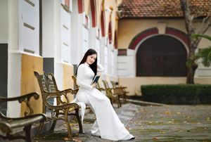 Elegant Vietnamese student in white Ao Dai reading, timeless beauty amidst classic architecture.-3