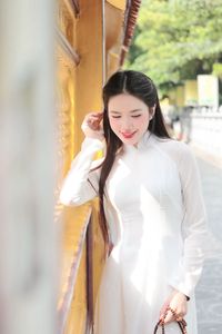 Elegant Vietnamese woman in traditional white Ao Dai, showcasing graceful beauty amidst ancient architecture.-3