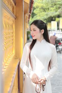 Elegant Vietnamese woman in traditional white Ao Dai, showcasing graceful beauty amidst ancient architecture.-7