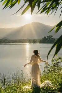 Golden Hour Serenity: Woman in White Dress Embracing Nature's Beauty by the Lake at Sunset.-6