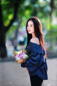 Elegant Beauty Charming Vietnamese Girl with Fresh Flowers on Street Captivating Street Fashion Style-0