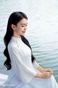 Elegant Vietnamese girl in traditional white Ao Dai by the lake, embodying cultural beauty-1