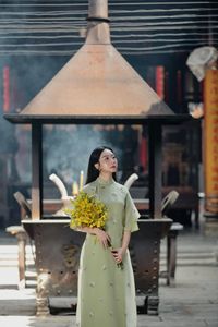 Graceful Vietnamese girl in green Ao Dai with yellow flowers at sacred pagoda-1
